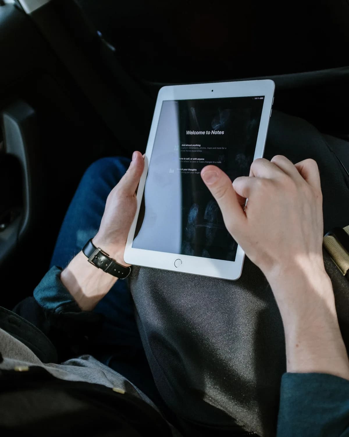 Hands holding a tablet inside a vehicle